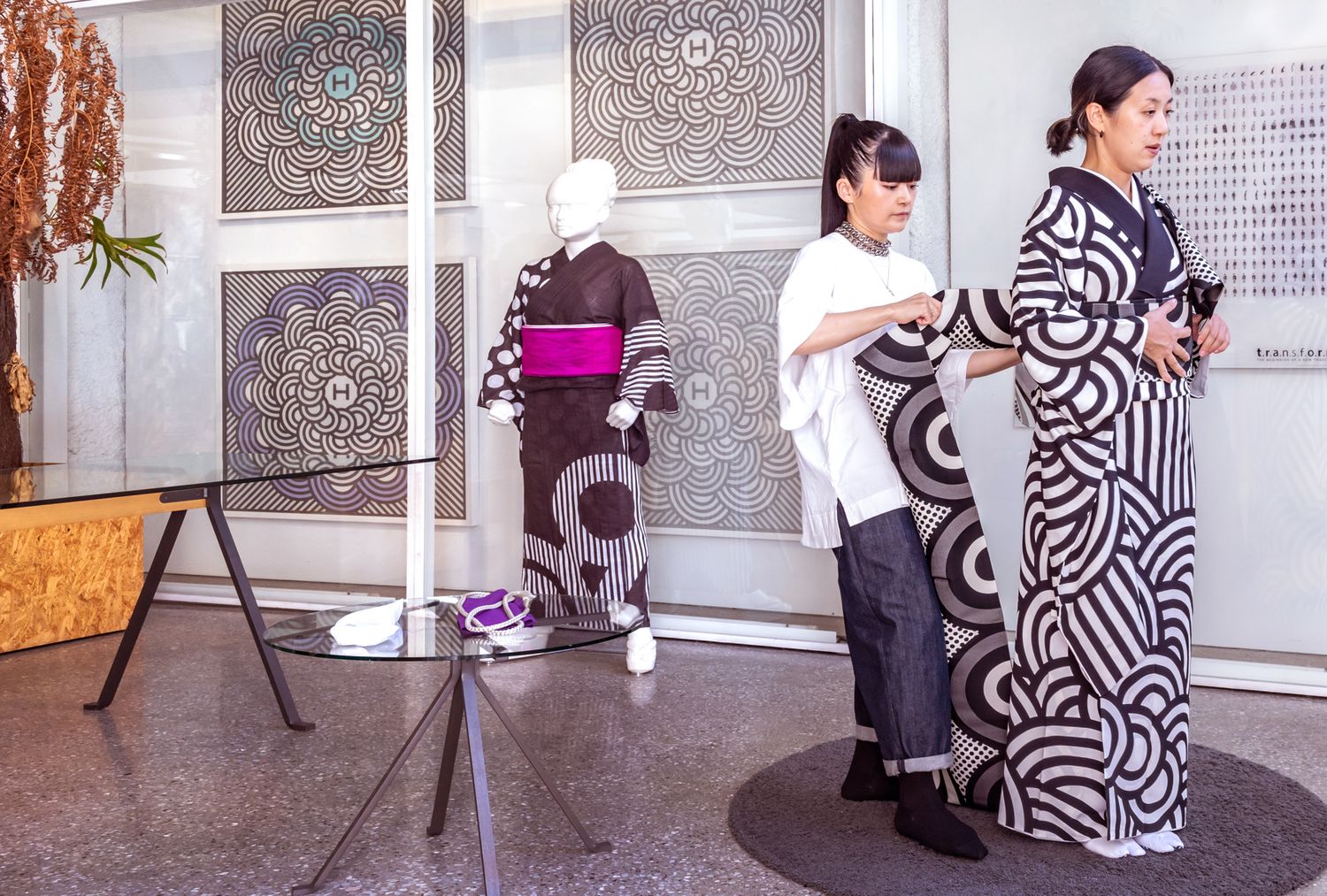 People arranging traditional Japanese kimonos on display in gallery setting.