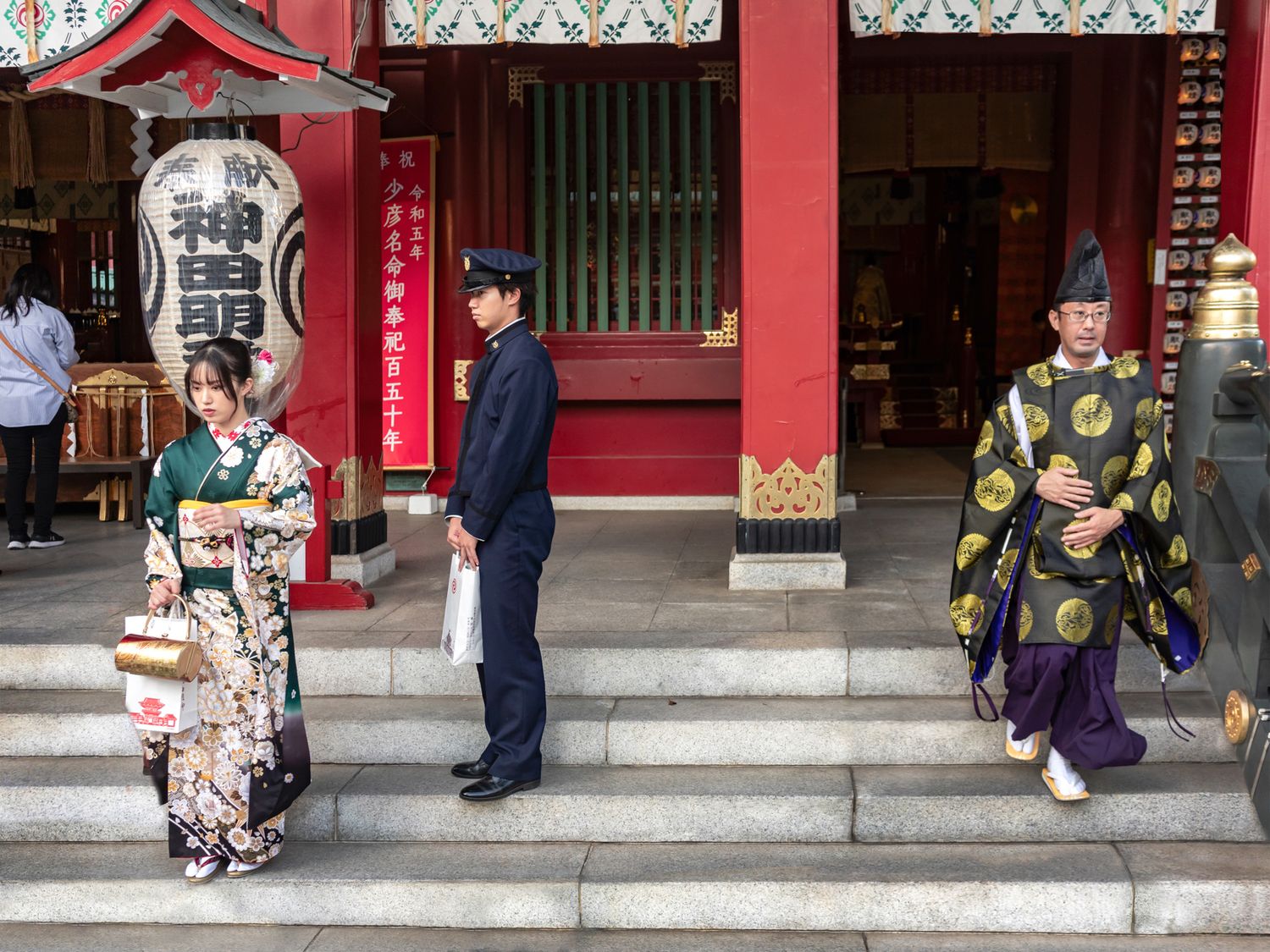 Traditional Japanese architecture with people in kimono standing on temple steps.