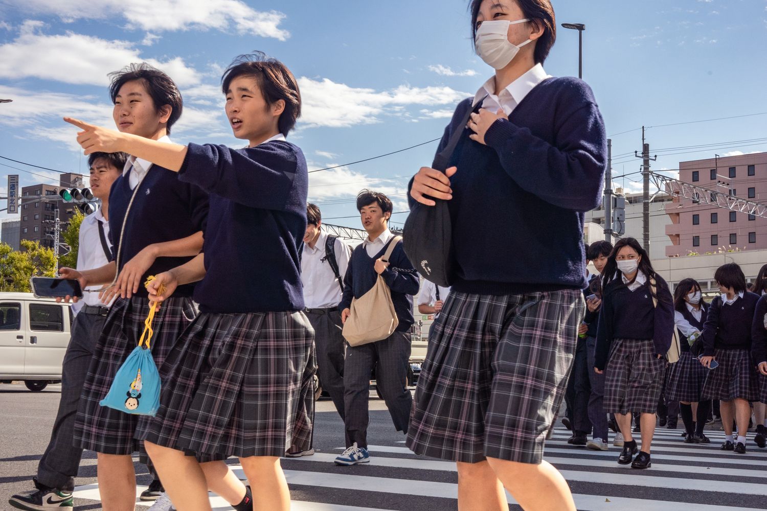Students in uniform crossing street during school commute in Japan.