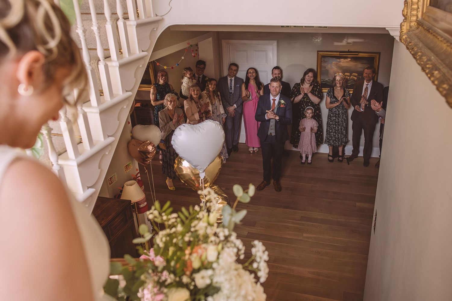 A wedding scene captures guests gathering in an elegant hallway as a person prepares to throw a bouquet.