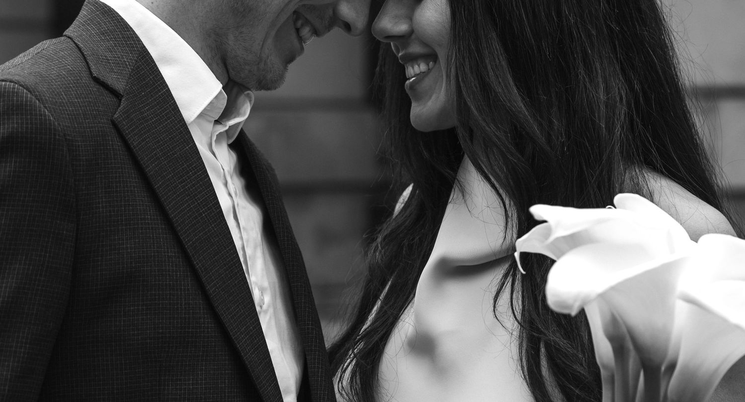 A romantic black and white close-up photo showing a couple intimately embracing and smiling together.