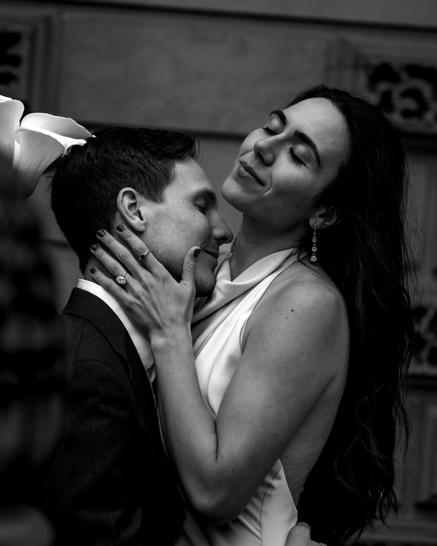 A romantic black and white portrait captures an intimate moment between a couple in elegant formal attire.