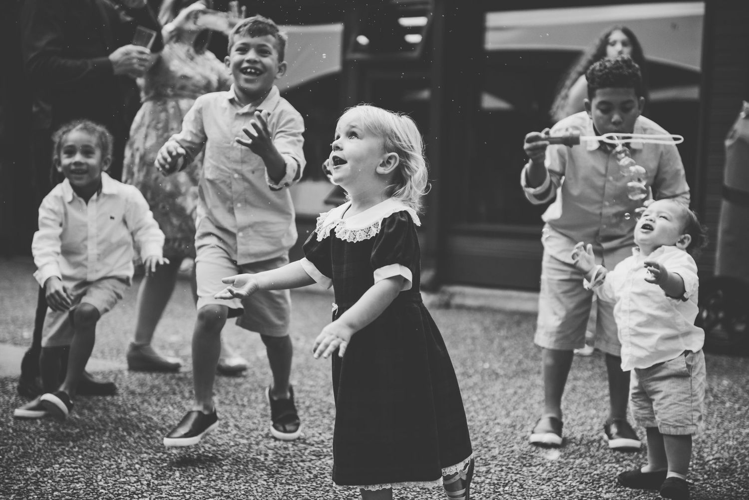 A vintage black and white photograph of children playing and jumping outdoors with joyful expressions.