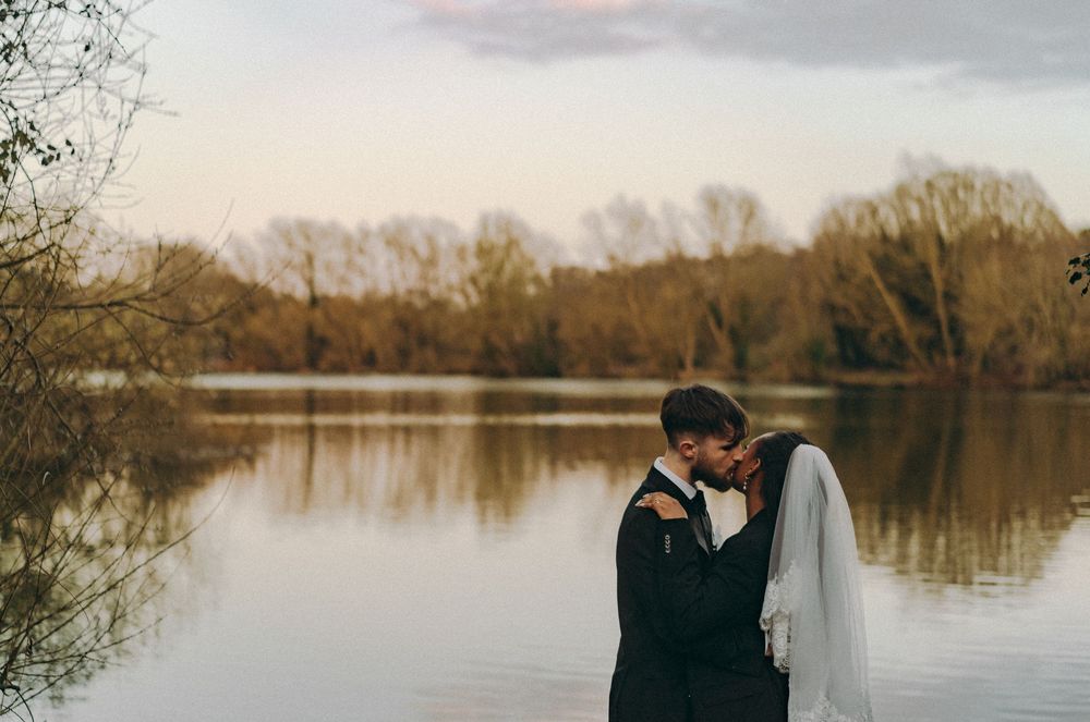 Bride groom sharing a kiss to the backdrop of a lake. Documentary wedding, Norwich