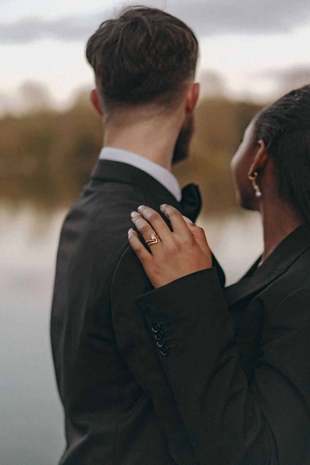 Close up photo of Bride groom in an embrace to the backdrop of a lake. Documentary wedding