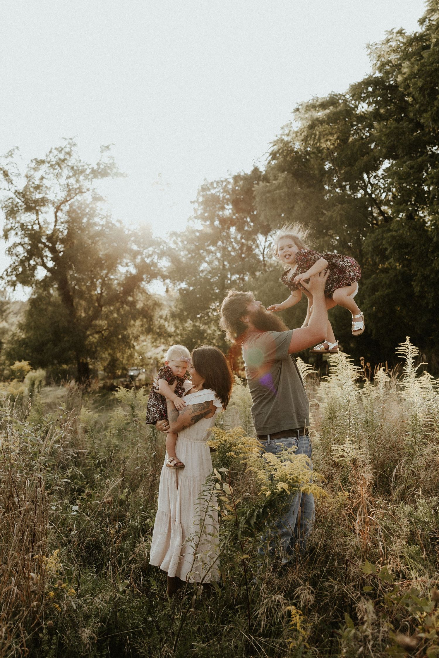Family enjoying a golden sunset in a wildflower meadow on a warm summer evening.