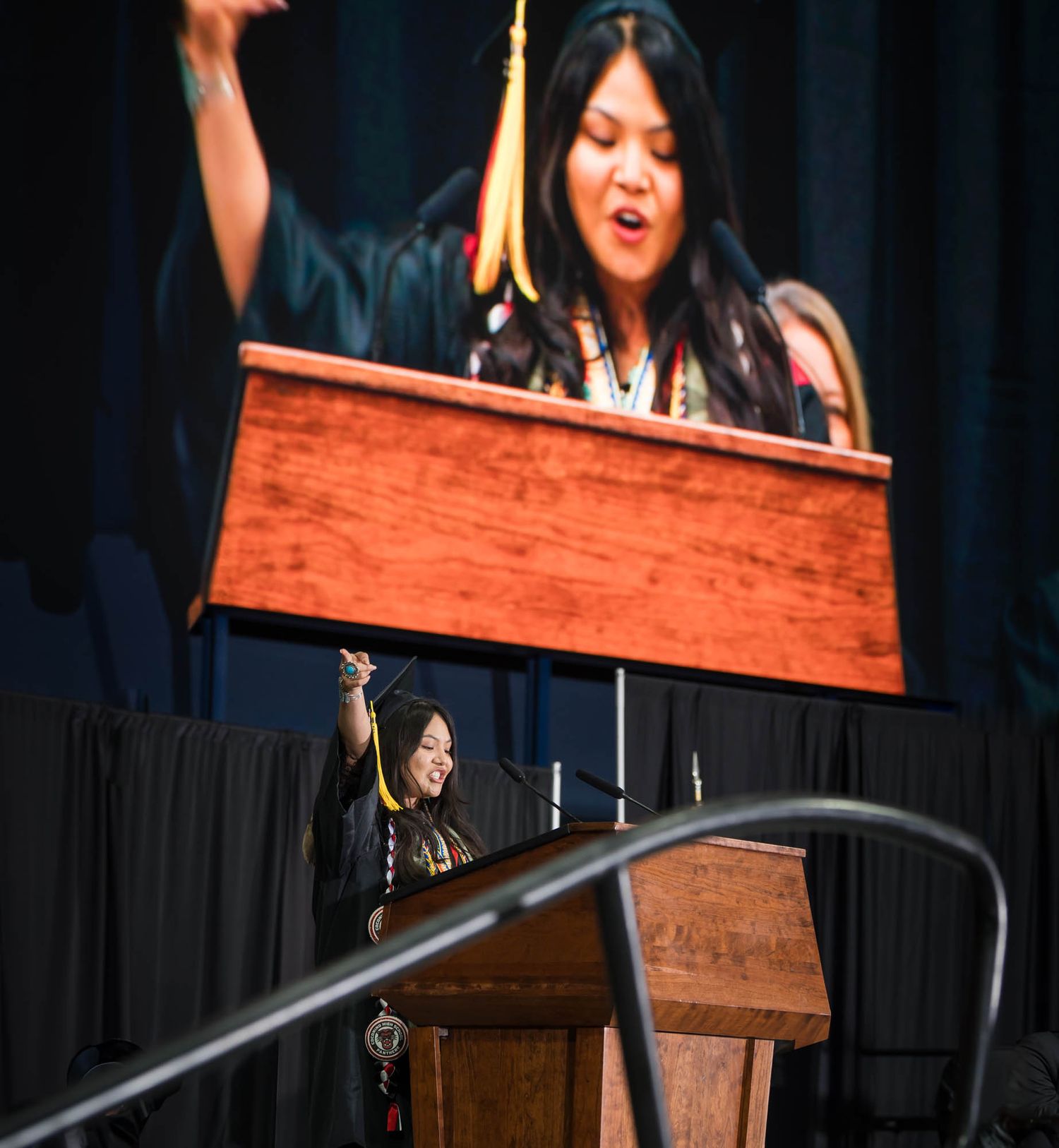 Elena Klopfenstein, standing at a podium, welcomed the 2025 CHS Graduation crowd in Navajo.