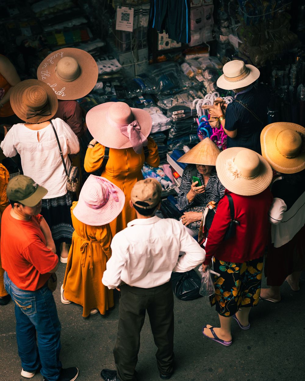 Group of people wearing straw hats gathered at outdoor market stall in Vietnam. Photograph by Chris Ha.