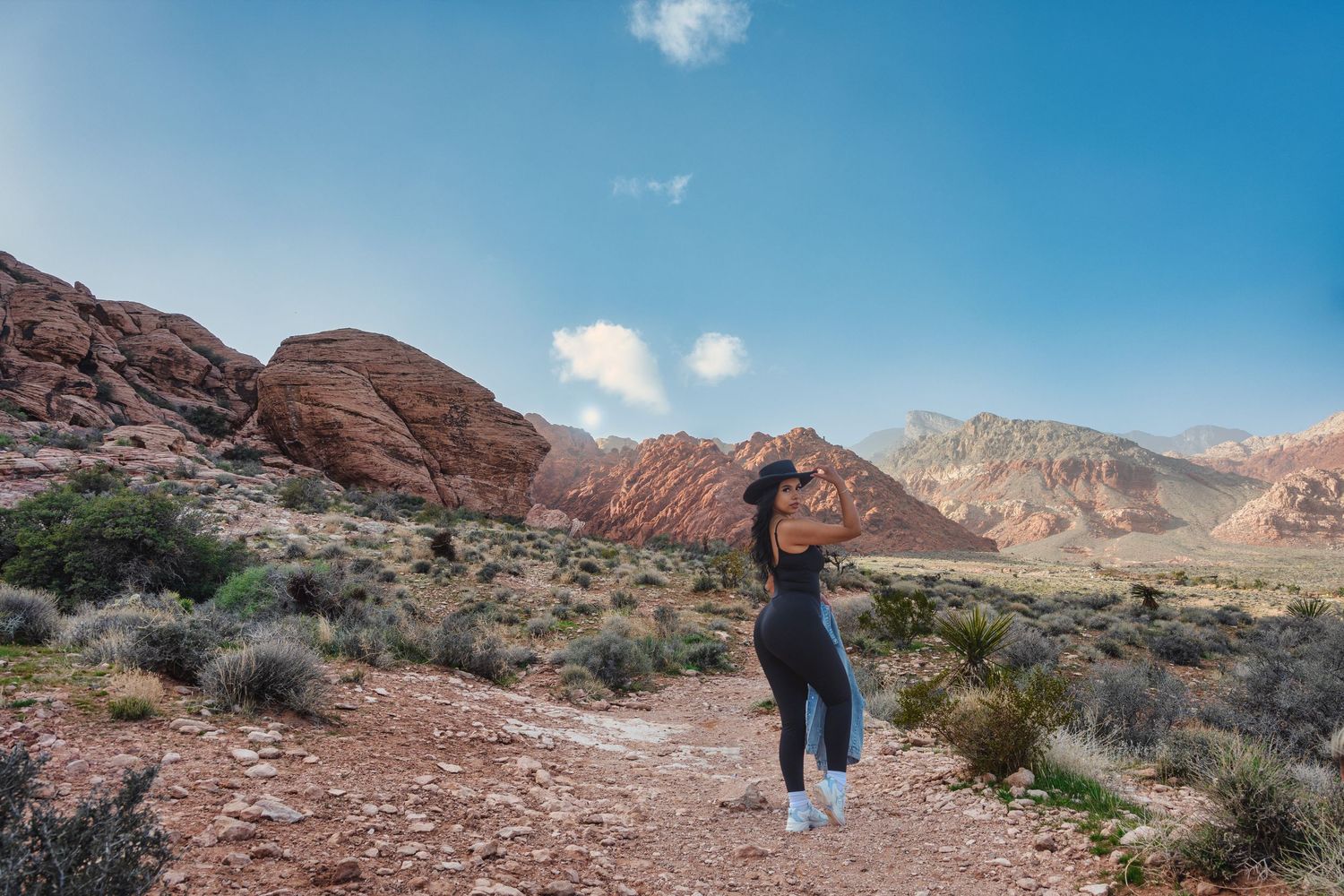 Woman hiking through red rock desert landscape under bright blue sky. Photo by Carolina Waldroff.