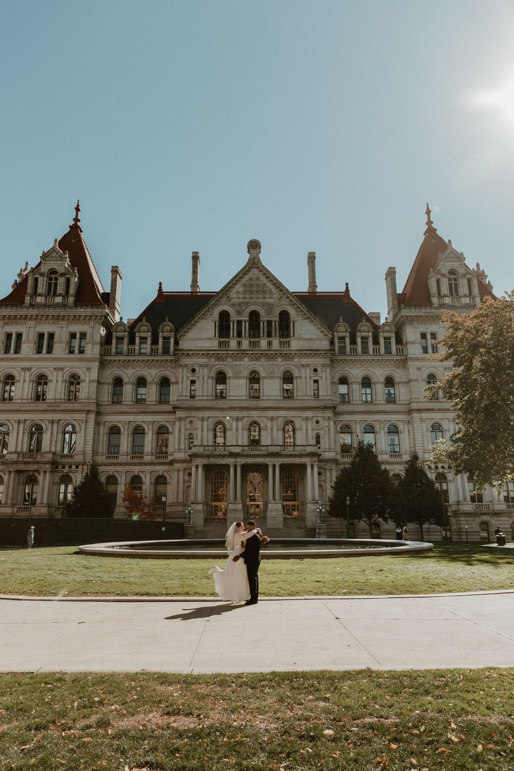 Wide shot of a historic mansion serving as an elegant wedding venue with couple in foreground.
