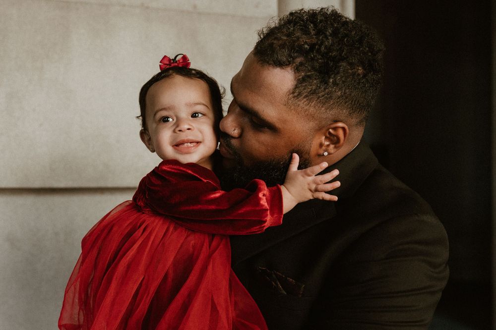 Sweet moment captured between a little girl in red dress and formal attire.