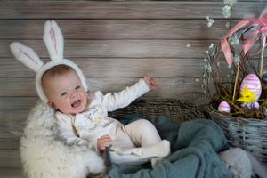 Easter holiday scene with bunny ears, basket of eggs and decorative items against wooden backdrop.