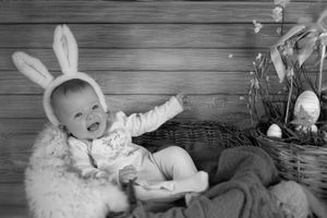 Black and white Easter portrait with bunny ears and decorative basket on rustic wooden background.