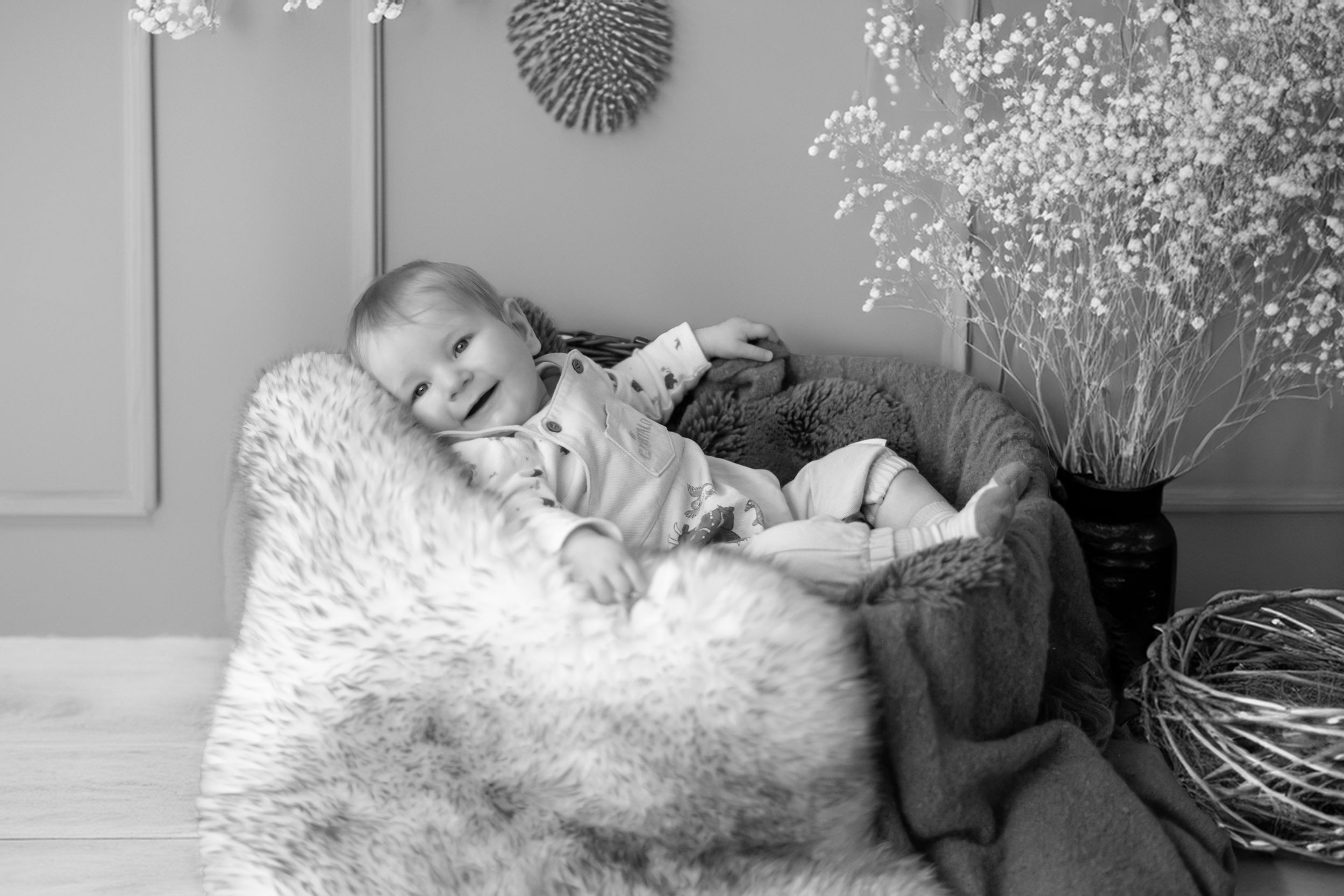 A peaceful sleeping scene in black and white with a soft fur blanket and delicate floral arrangement in the background.
