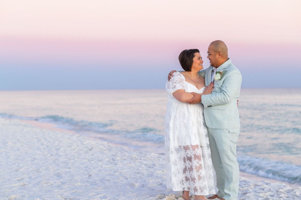 A couple shares a romantic moment at sunset on a pristine white sand beach.