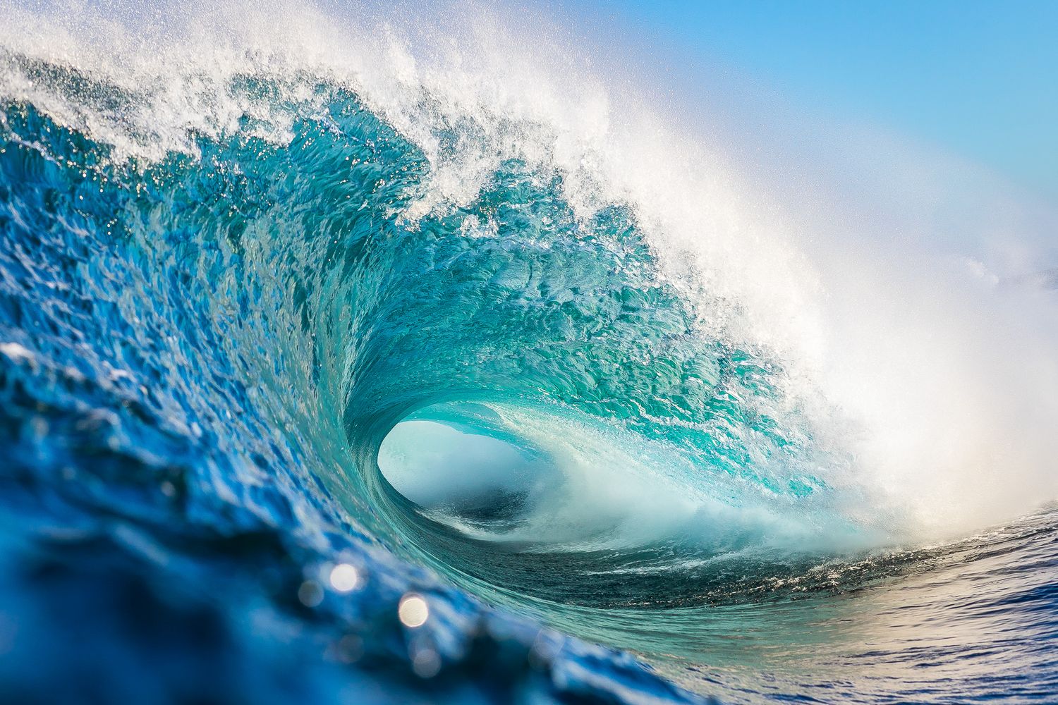 Stunning sequence of turquoise ocean waves curling and breaking in crystal clear water against a bright sky.