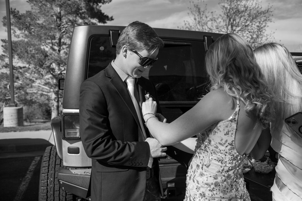 Girlfriend placing flowers on Boyfriends suit jacket.