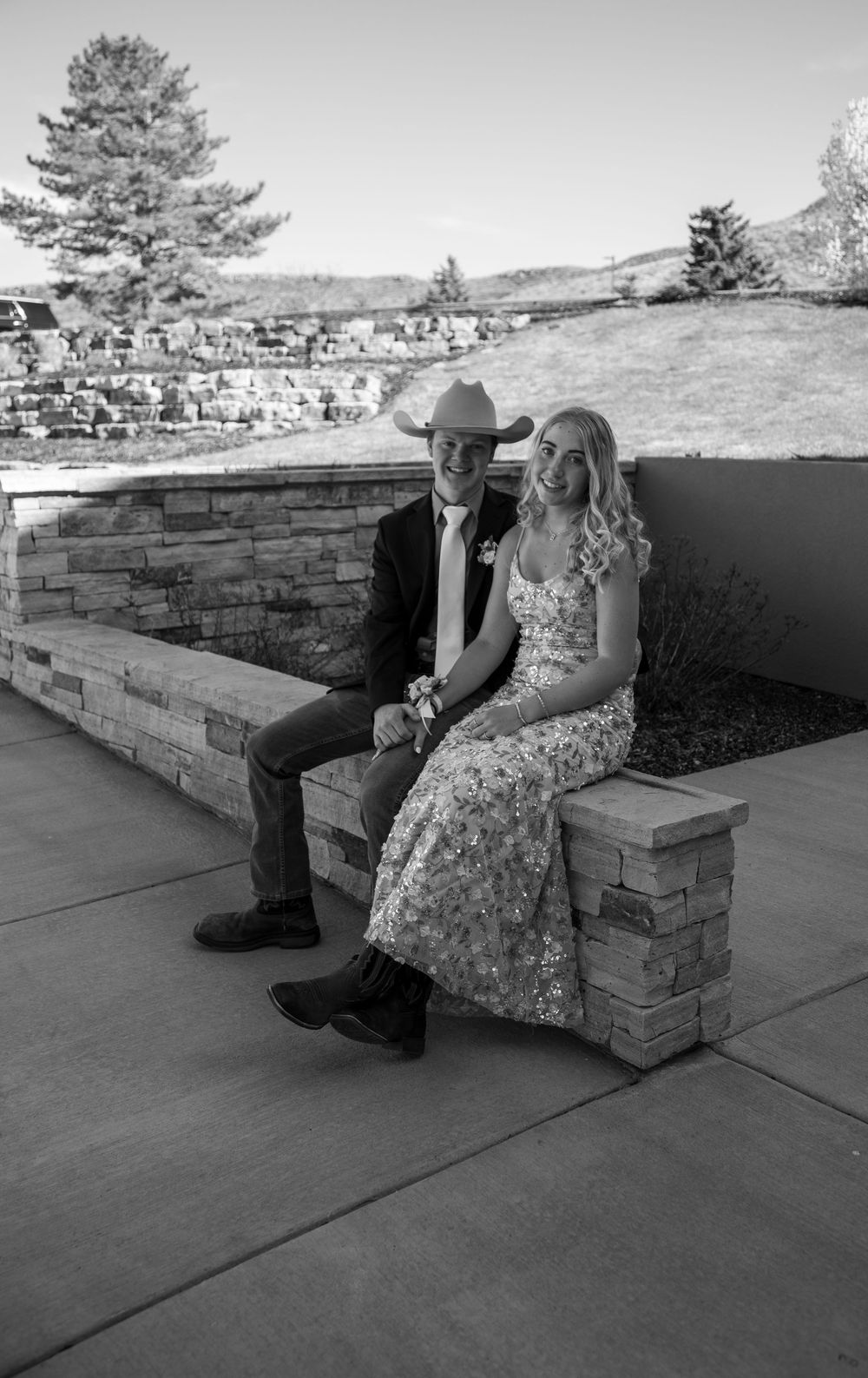 Prom couple sitting on a ledge.