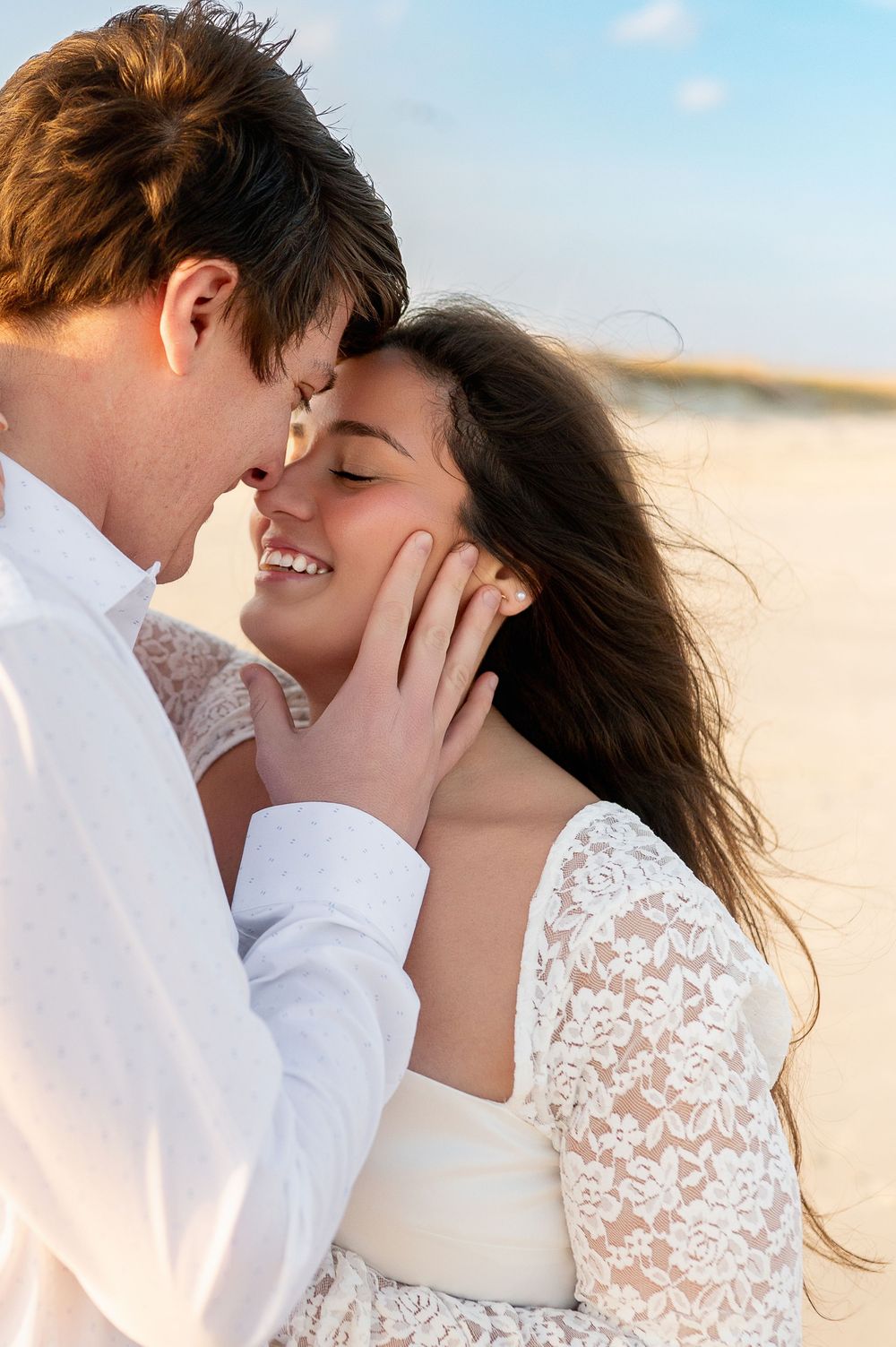 Close-up romantic portraits on beach showing intimate moments between couple in white attire.