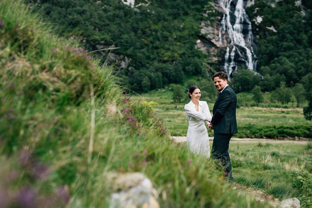 Scenic outdoor wedding ceremony setting with mountains and waterfalls in the background.