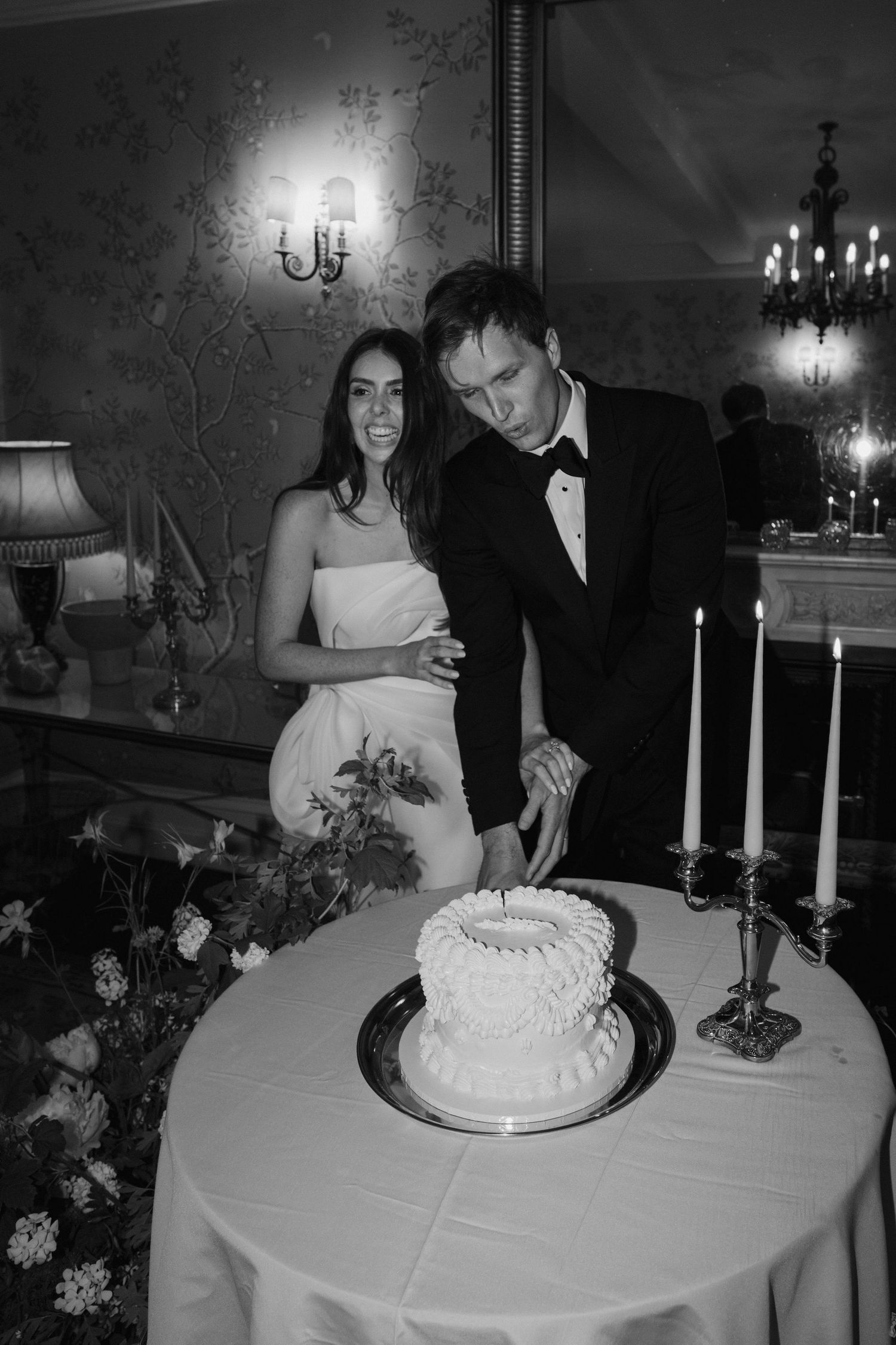 groom cutting the wedding cake as the bride laughs at dewsall court in herefordshire