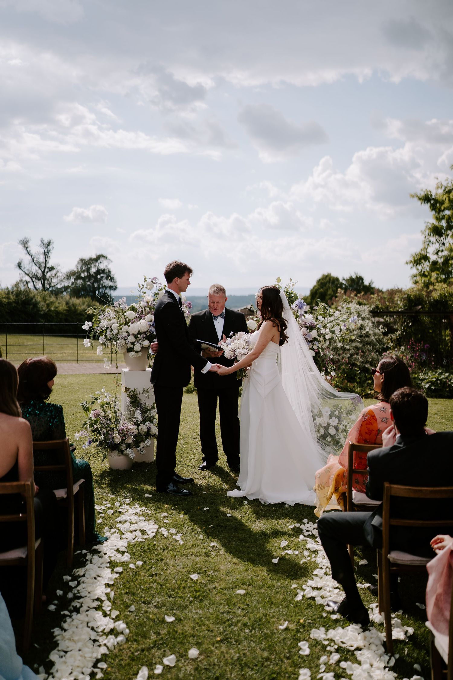 bride and groom at the alter, holding hands on the lawn, surrounded by their wedding guests at dewsall court in herefordshire