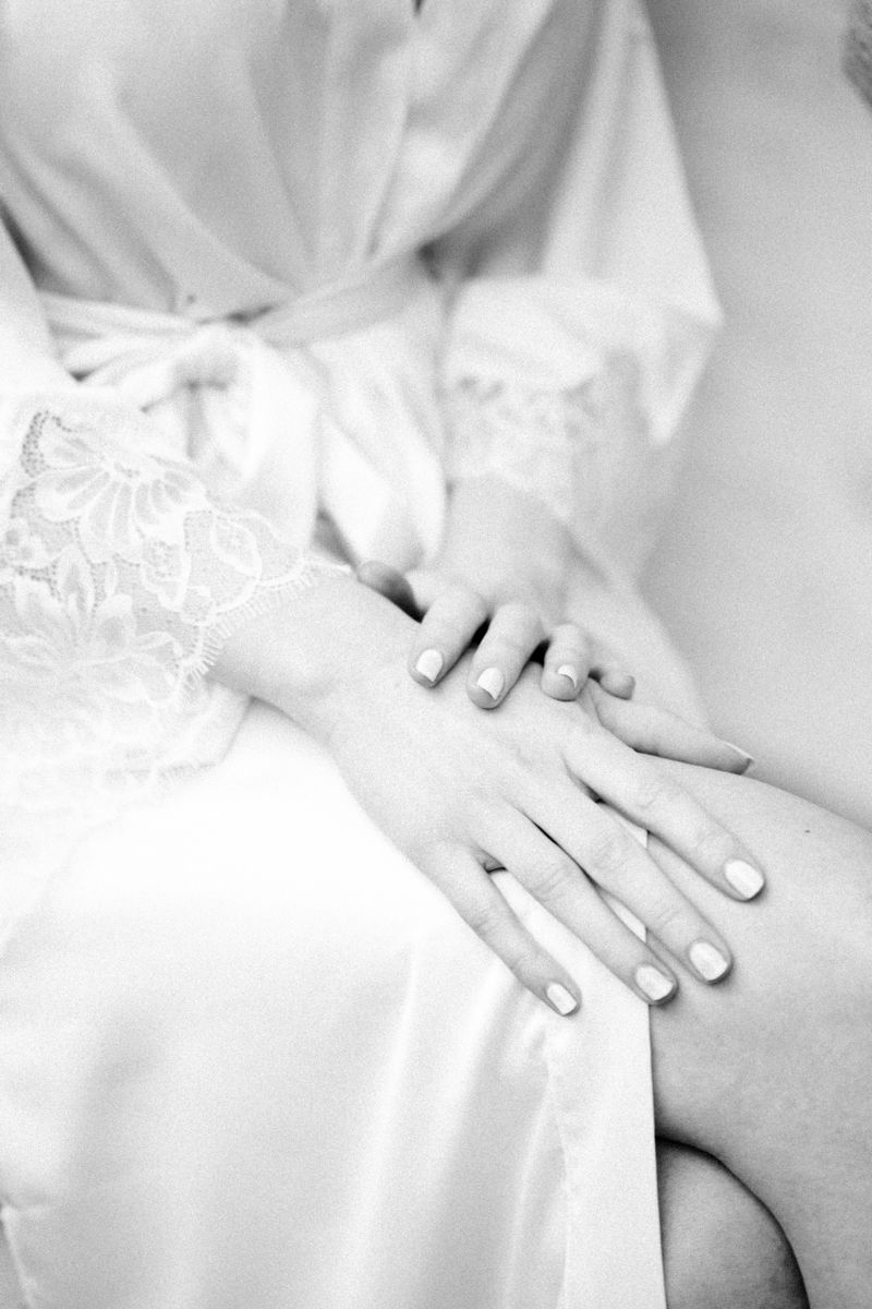 Schwarz-Weiss Bild einer Braut im Morgenmantel mit gefalteten Händen beim Getting Ready vor der Hochzeit.