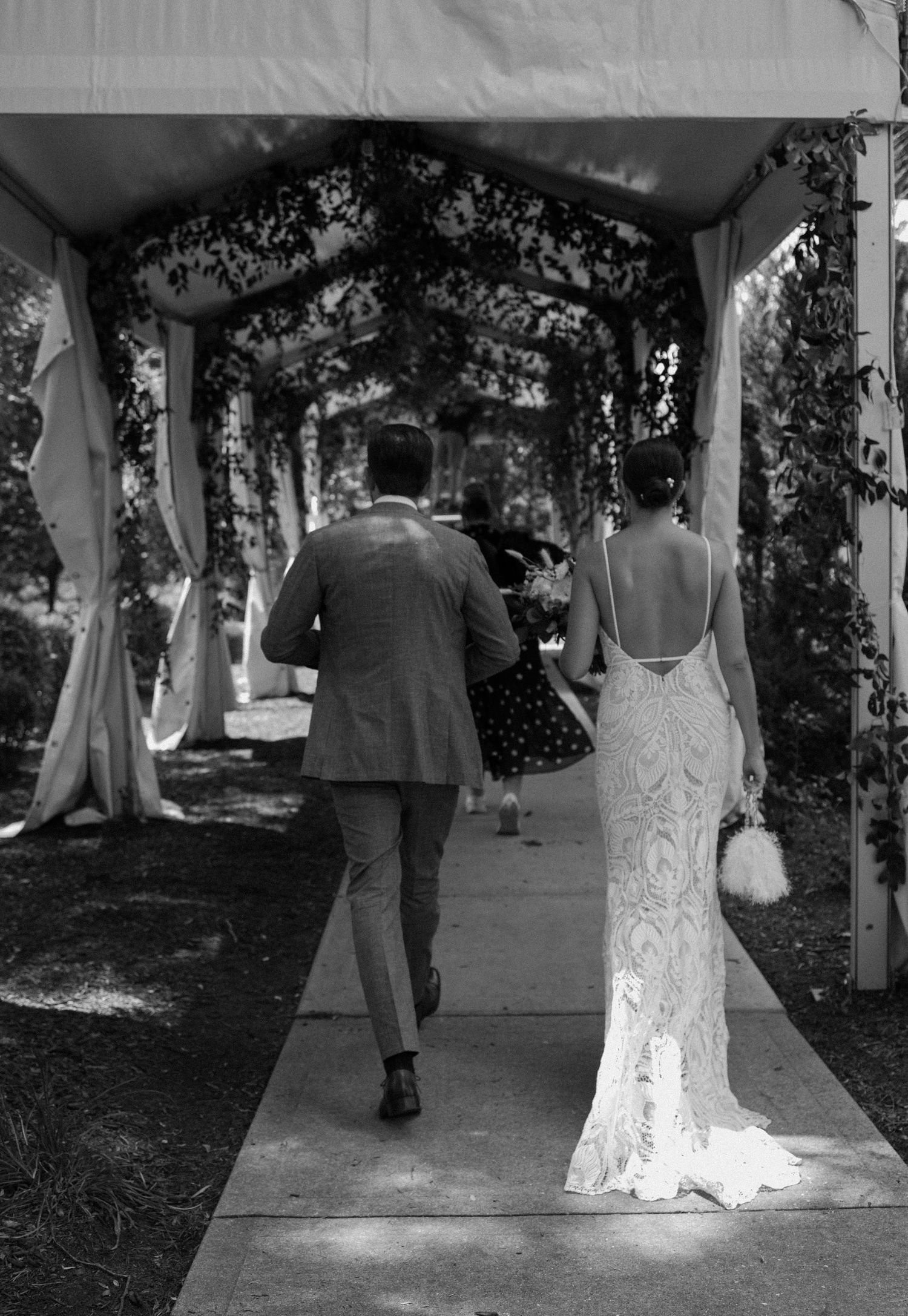 Outdoor wedding ceremony overlooking a lake with guests seated in white chairs on a grassy lawn.