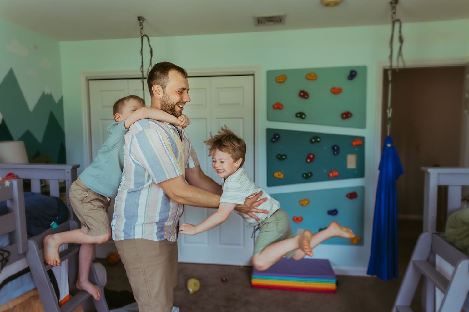 A parent and child practice dance moves together in a colorful room with decorated walls.