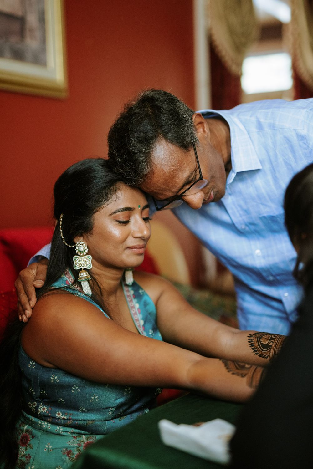 A couple in traditional Indian attire share a tender moment while dancing at a formal event.