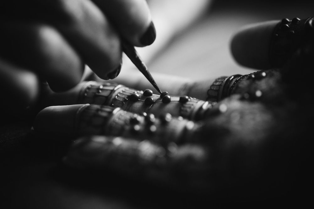 Close-up macro photography shows hands working with electronic components and soldering equipment on a circuit board.