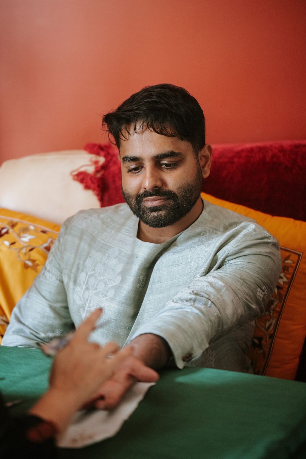 Person resting on colorful bedding with pillows in warm lighting.