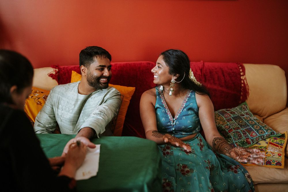 People share a joyful moment while sitting on a red couch with colorful cushions in a casual indoor setting.