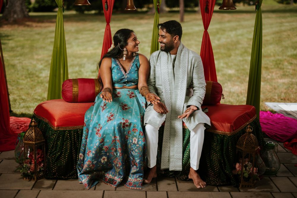 Couple sitting together on outdoor patio with red cushions.