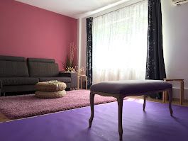 Contemporary bedroom space with dark furniture against pink walls and purple bedding visible.