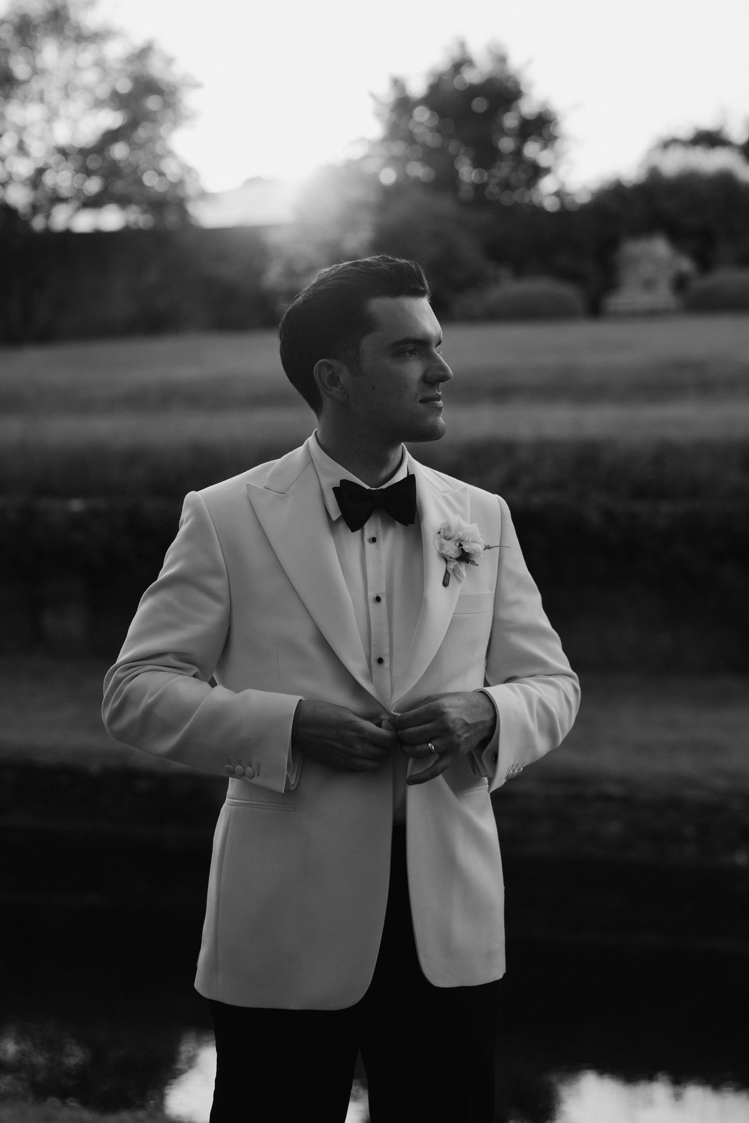 groom fastening jacket button at dusk at hamswell house in bath