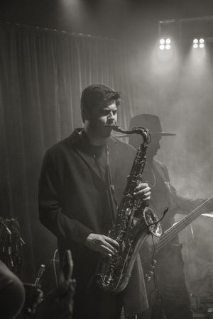 Moody black and white sequence of a saxophone player performing in atmospheric stage lighting and fog.