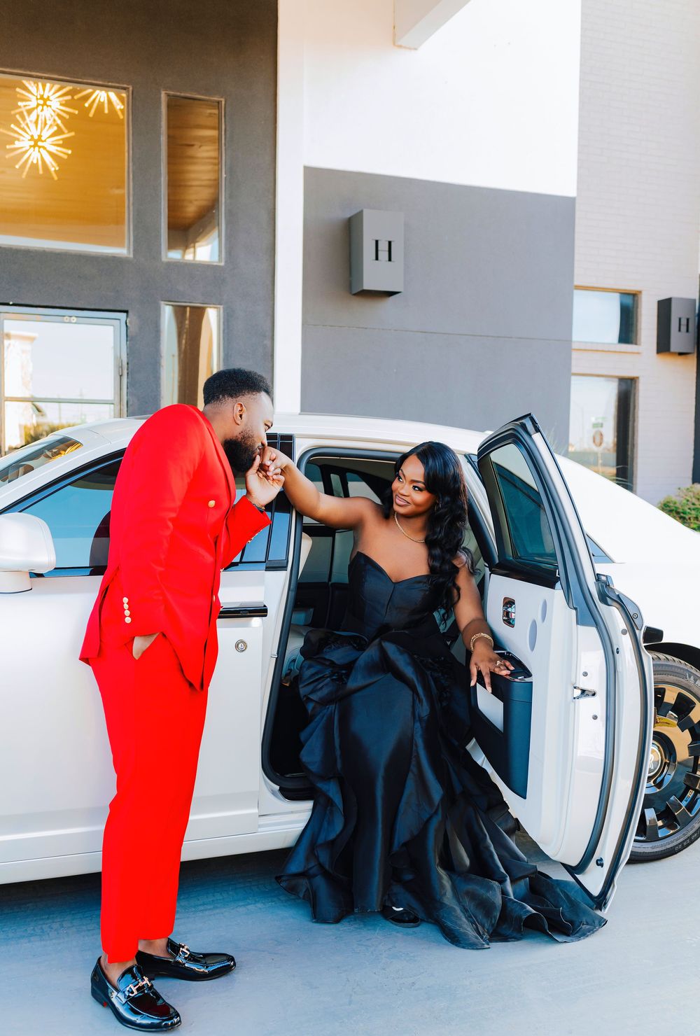A sequence of photos showing a romantic proposal moment in front of parked cars with someone in red kneeling before another in black.