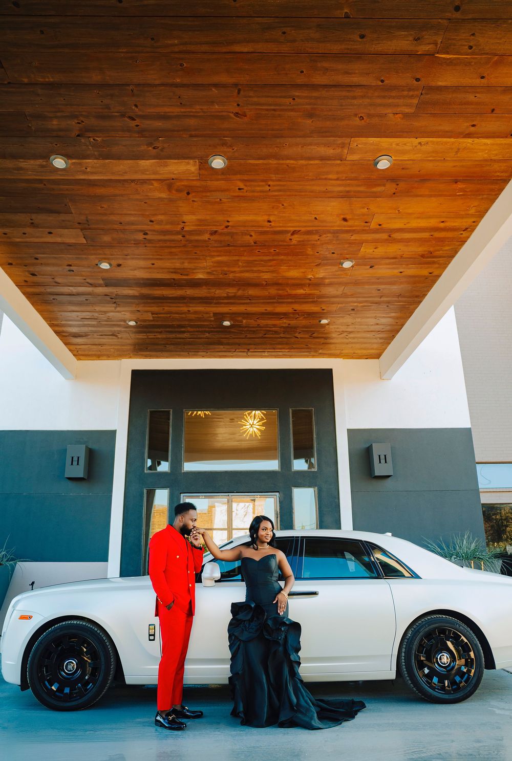 Multiple white luxury vehicles parked in a covered area with wooden ceiling.