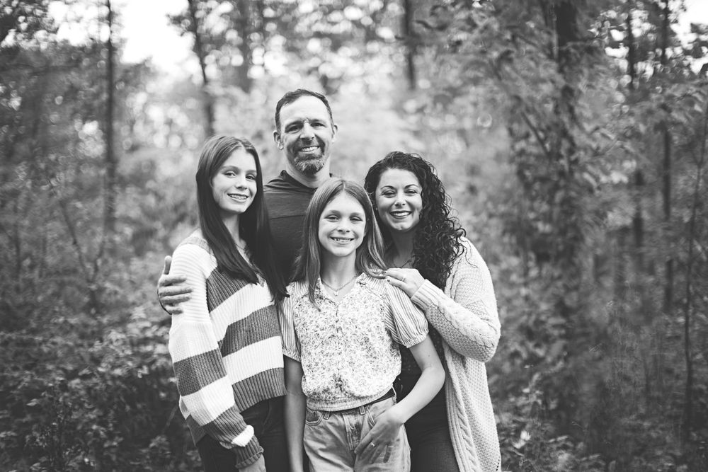 A family shares joyful moments together in a black and white outdoor photo session.
