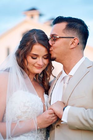 Romantic wedding portrait series with soft pastel sky background.