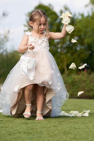 Flower petals scatter on grass as white dress and sandals are captured in a series of artistic wedding photos.