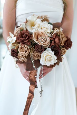 Elegant wedding bouquets featuring cream and brown roses with crystal accents and satin ribbon wrapping.