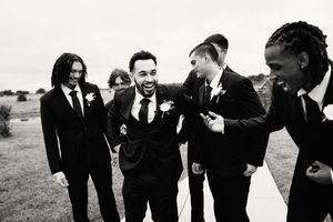 Wedding party laughs together in black and white photo showing candid moment of joy and celebration.