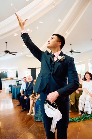 Groomsmen in dark suits perform synchronized dance moves during a wedding reception in a bright venue.