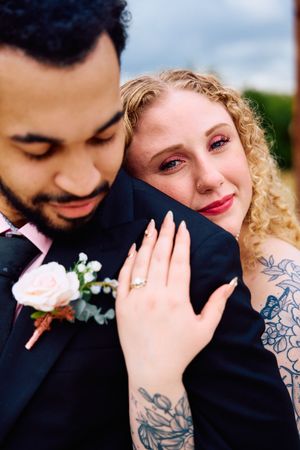 Close-up romantic moment captured showing tattoos and floral details.