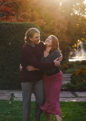 A couple embraces and laughs together in a garden during golden hour sunset.