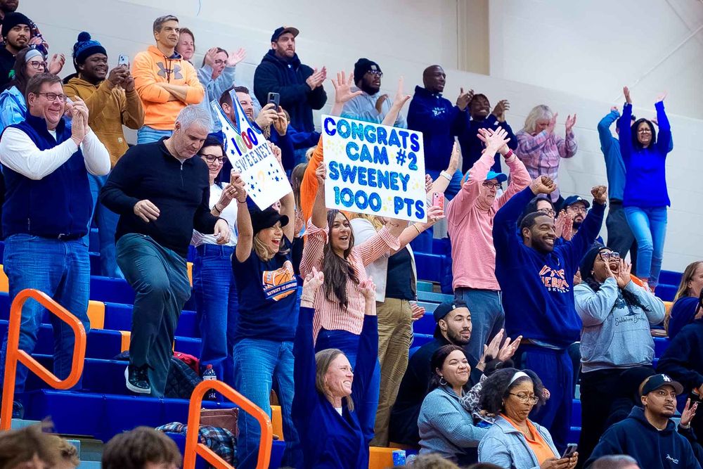 Hershey High School crowd celebrates in the bleachers with “Congrats Cam Sweeney 1,000 pts” signs during the basketball game.