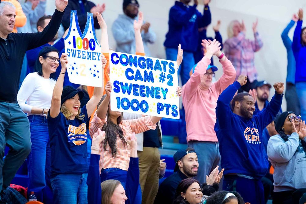 Fans in the stands hold up congratulatory signs and cheer for Cam Sweeney’s 1,000th career point at Hershey High School.