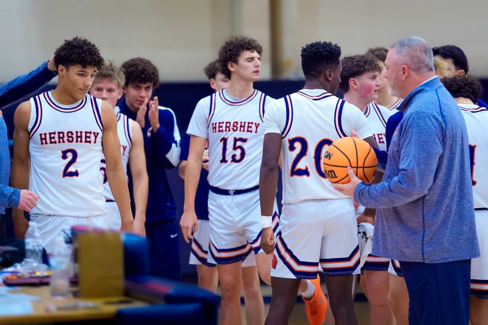 Cam Sweeney stands with Hershey High School teammates and coach, holding the game ball to celebrate his 1,000th career point.